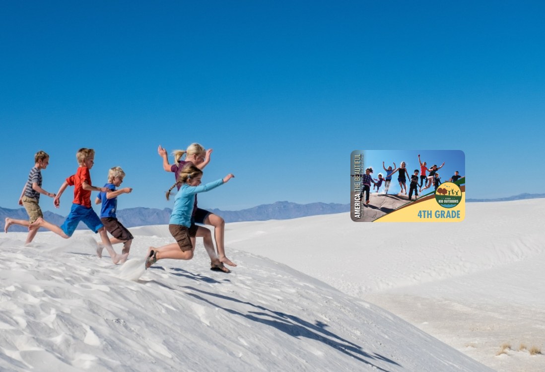Gruppe von Kindern, die über eine weiße Sanddüne in Death Valley National Park laufen, mit Hügeln und einem klaren blauen Himmel im Hintergrund und einer Werbekarte auf der rechten Seite.