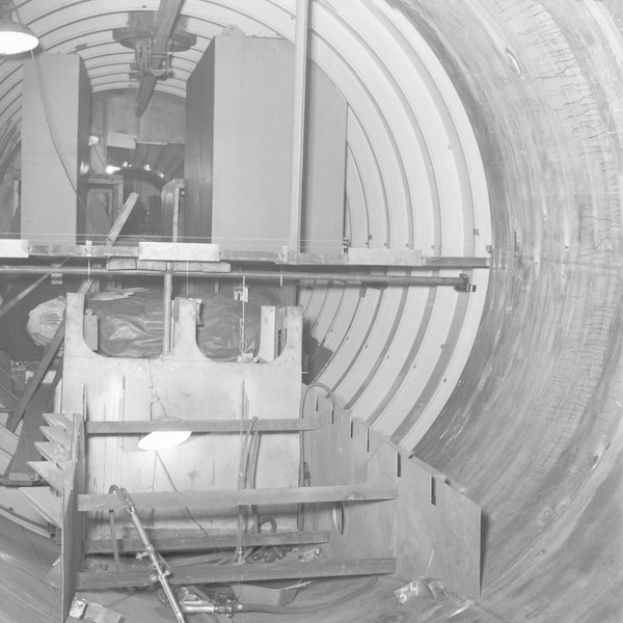 Schwarzes und weißes Foto eines großen Tunnels mit einer Lampe am Ende und einigen sichtbaren Objekten im Inneren.