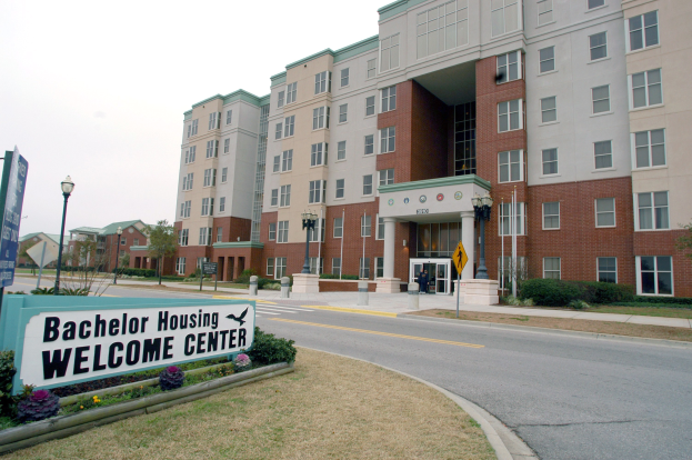 Ein Willkommenszentrum für Bachelor-Wohnheime mit Gebäuden, Straßeninfrastruktur, Fahrzeugen, Grünflächen und einem klaren Himmel.