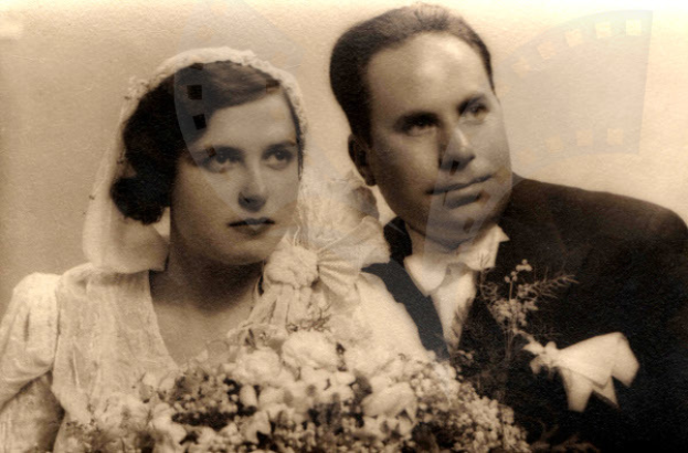 Ein Mann und eine Frau in feierlicher Kleidung lächeln glücklich auf ihrer Hochzeit, die Frau hält einen Blumenstrauß.