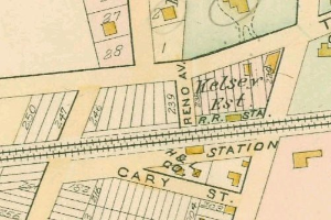 Alte Stadtkarte einer dicht bebauten Stadt mit nummerierten Parzellen, Textanmerkungen und einer 'Grundstück-zu-Verkauf'-Anzeige unten.