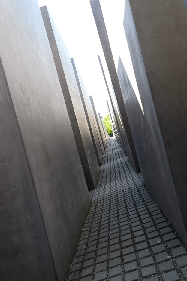 Luftaufnahme des Holocaust-Mahnmals für die ermordeten Juden Europas in Berlin mit parallelen Betonsteinen und umliegenden Bäumen unter einem klaren Himmel.