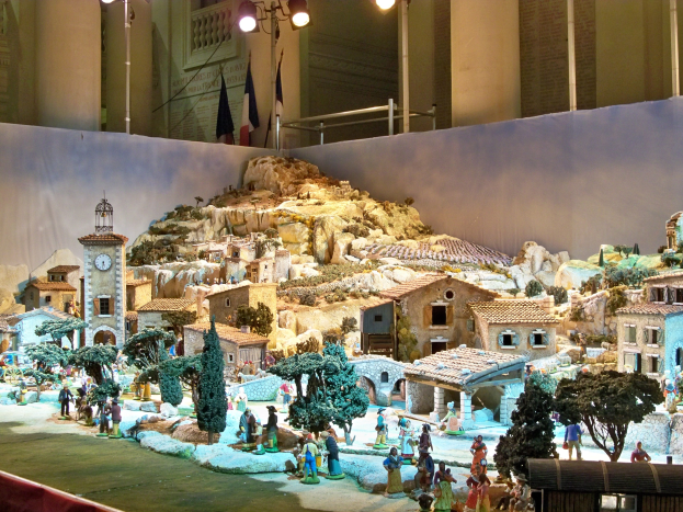 Ein detailliertes Miniatur-Modell einer Krippe in einem Museum ausgestellt, mit Figuren, Strukturen und beleuchteten Elementen, die eine festliche Atmosphäre schaffen.