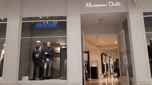 Innenansicht des Massimo Dutti Geschäftes in Mailand mit Schaufensterpuppen in aktueller Mode, Deckenbeleuchtung, Informationsschildern und Türen.