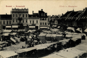 Schwarz-weiß-Foto eines vollen Marktes in Kronstadt, Deutschland, mit Menschen, Zelten und Gebäuden im Hintergrund.