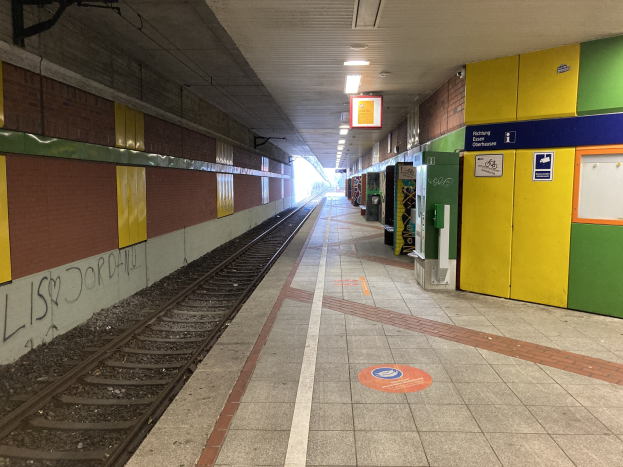 Ein Bahnsteig mit einem Zug auf den Gleisen, beleuchtet von Deckenleuchten, mit Graffiti an einer linken Wand und ein paar Gegenständen auf der rechten Seite, identifiziert als Berlin Hauptbahnhof in Berlin, Deutschland.