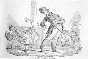 Cartoon of a man in a top hat and tails standing in front of a crowd, with a pole and fence in the background, labeled "April Fool's Day" at the bottom.