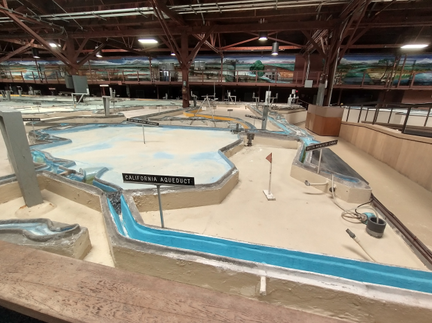 Großes Indoor-Wasserpark mit mehreren Wasserbahnen, Deckenbeleuchtung, Wandgemälden und einem Minigolf-Platz.