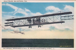 Ein altes Foto des größten US-Flugzeugs in der Luft, mit sichtbaren Passagieren und Wolken am Himmel, mit Text unten.