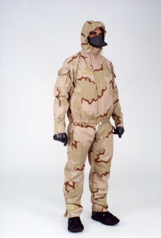 Ein Mann in einem Tarnmuster-Schutzoverall und passender Maske steht vor einem weißen Hintergrund.