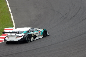 Ein silberner Mercedes-AMG GT3 Rennwagen auf einer Rennstrecke mit Text auf der Karosserie und Gras links.