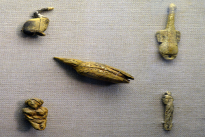 Eine Glasvitrine zeigt eine Sammlung von altägyptischen Artefakten, die auf einem Tuch angeordnet sind und ihre feinen Details präsentieren.