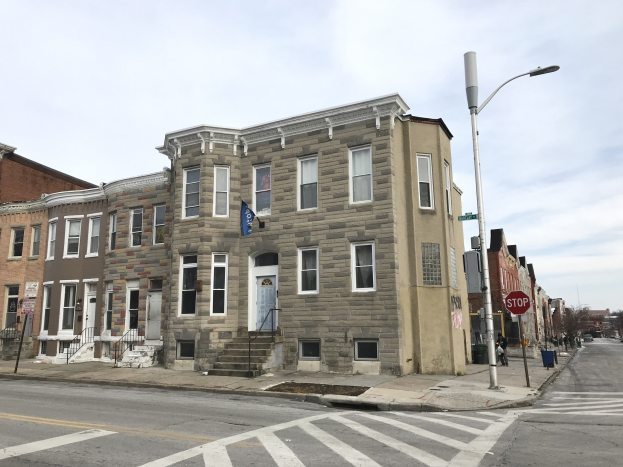 Reihe moderner Häuser an einer Straßenecke in Philadelphia mit Fahrzeugen, Straßenschildern und Bäumen im Hintergrund.
