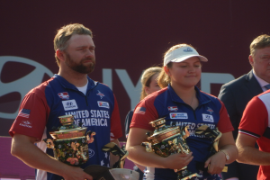 Gruppe von Menschen mit Trophäen neben einer Tafel mit der Aufschrift "Weltarcherie-Meisterschaften."