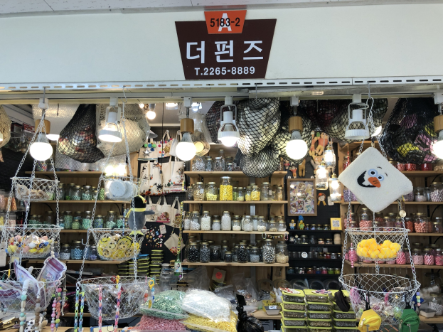 Ein unordentlicher Laden in Seoul, der verschiedene Gegenstände wie Körbe, Lichter, Flaschen und Spielzeuge anbietet, mit einem Schild öber dem Eingang, das ihn als einen der besten koreanischen Läden ausweist.